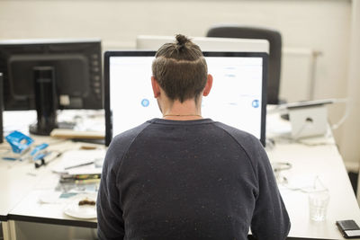 Rear view of businessman using computer in creative office
