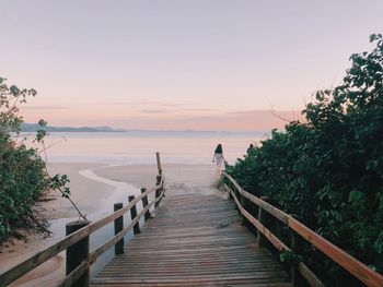 Woman walking at beach against sky during sunset