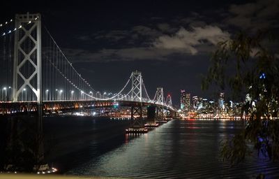 Illuminated bay bridge over river at night