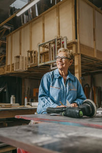 Smiling senior female carpenter contemplating at workshop