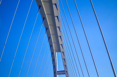 Low angle view of suspension bridge against blue sky