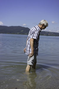 Side view of senior man in kochelsee against sky