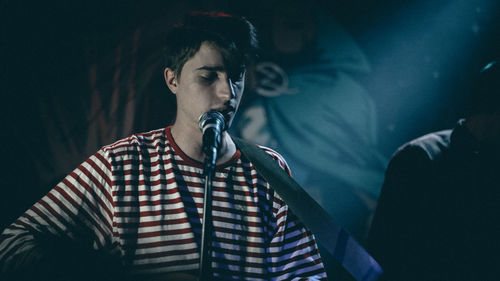 Young man singing on microphone in concert