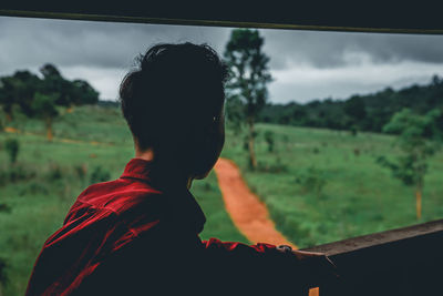 Man standing by railing against landscape and sky