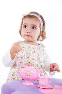 Cute girl sitting against pink and white background