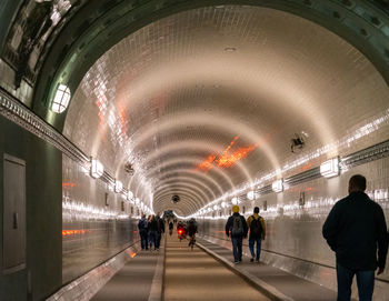 People walking in illuminated tunnel