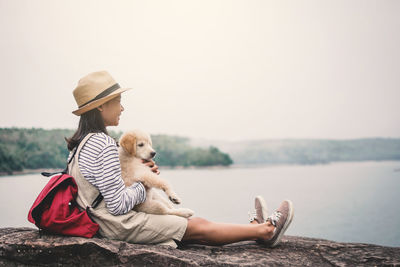 Midsection of woman with dog sitting against the sky