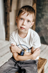 Young little caucasian child with green eyes in a white t-shirt, with a wrist watch