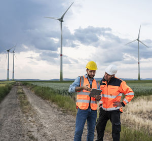Engineers working together with tablet computer at wind farm