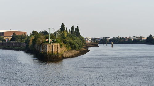 Scenic view of river by buildings against clear sky