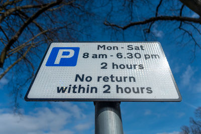 Low angle view of signboard against blue sky