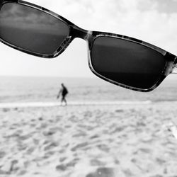 Close-up of sunglasses on beach against sky