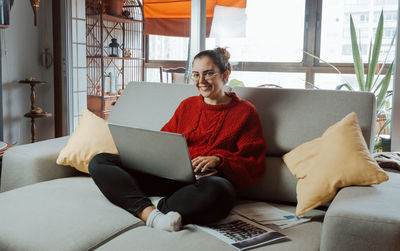 Man using laptop while sitting on sofa at home