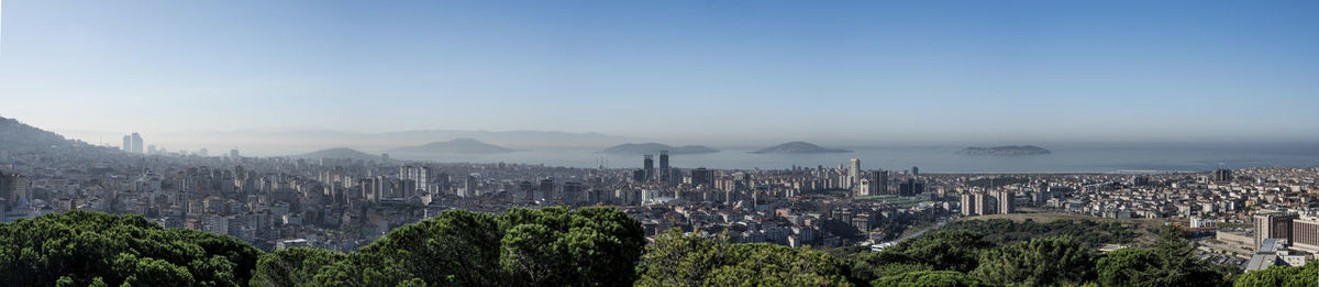 Panoramic view of buildings and trees against sky