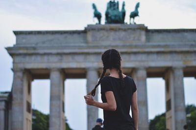 Rear view of woman standing in front of historical building