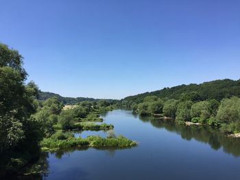 Scenic view of lake in forest against clear blue sky