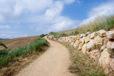 Road amidst field against sky