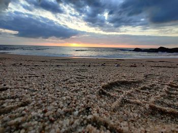Surface level of beach against sky during sunset