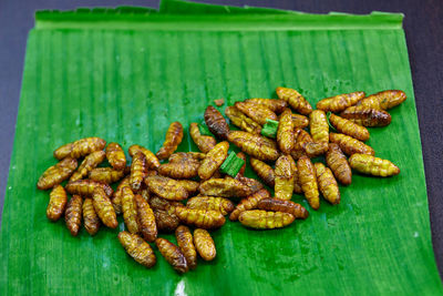 Fried silkworm pupae on green banana leaf