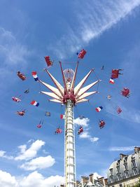 Low angle view of chain swing ride spinning against blue sky