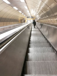 Rear view of woman walking on escalator