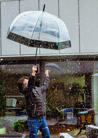 Side view of man with umbrella on puddle