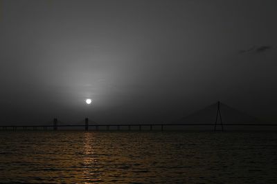 Silhouette of bridge over sea at night