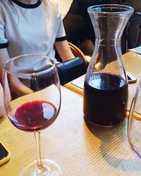 Midsection of woman pouring wine in glass on table