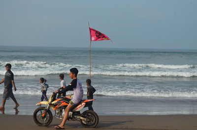 People on beach by sea against sky