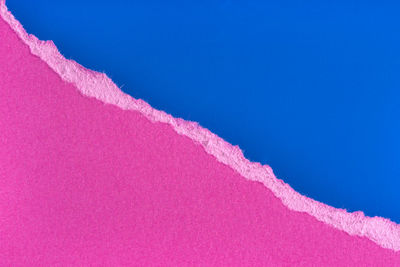 Low angle view of pink vapor trail against clear blue sky