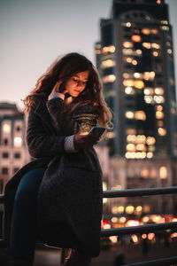 Young woman standing in illuminated city at night