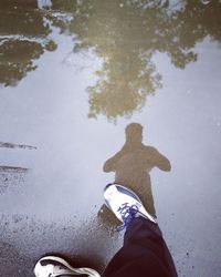 Low section of person standing on puddle during rainy season