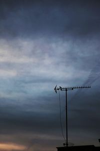 Low angle view of silhouette birds perching on cable against sky