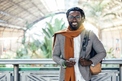 Portrait of businessman using phone while standing at airport