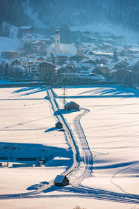 Aerial view of snow covered land by sea during winter