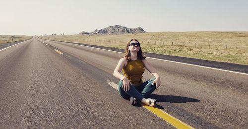 Portrait of young woman on road against sky