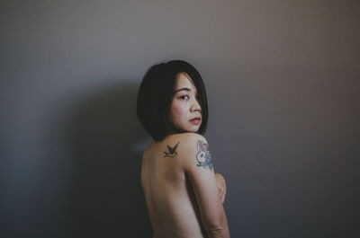 Portrait of young woman standing against wall