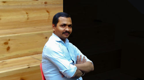 Portrait of young man standing against wall