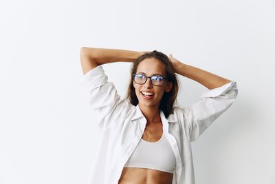 Portrait of young woman standing against white background