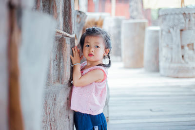 Cute girl standing by wall at alley