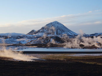 Scenic view of volcanic landscape and snowcapped mountains against sky