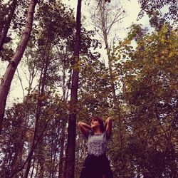 Woman standing by tree in forest