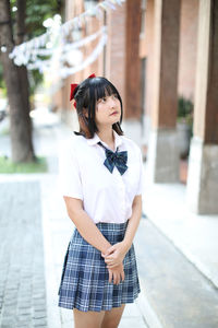 Young woman looking away while standing outdoors