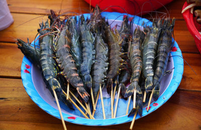 Plate full of prepped prawns on skewers ready for barbecue