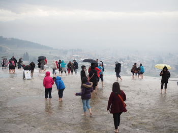 People on wet landscape against sky during rainy season