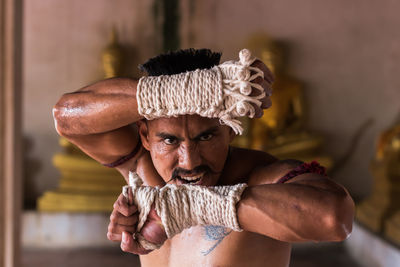 Close-up portrait of male fighter standing against sculptures