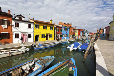 Boats moored at harbor against buildings in city