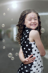 Close-up of smiling girl standing against wall