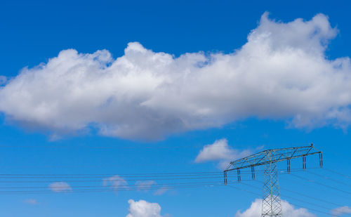 Low angle view of electricity pylon against blue sky