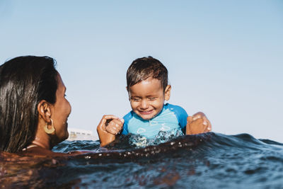 Portrait of a young mother and son playing at sea